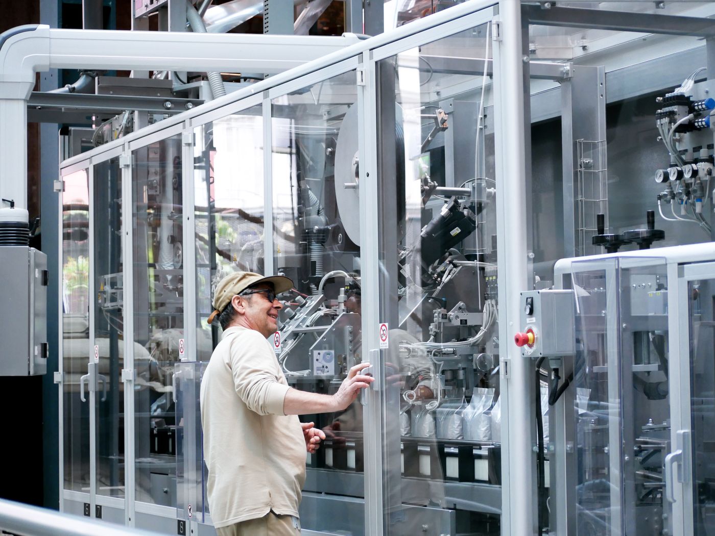 A person beside enclosed coffee packaging machinery